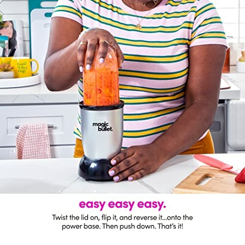 Person using Magic Bullet blender with orange mixture.