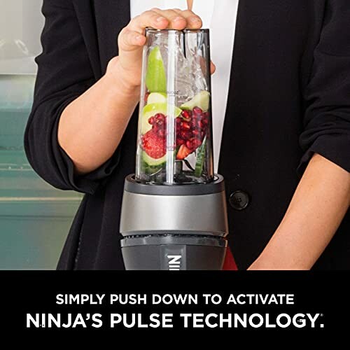 Person using Ninja blender with fruits inside.