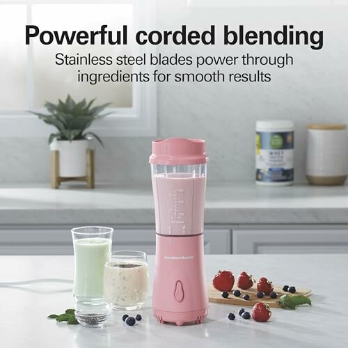Pink blender with drinks and berries on kitchen counter.