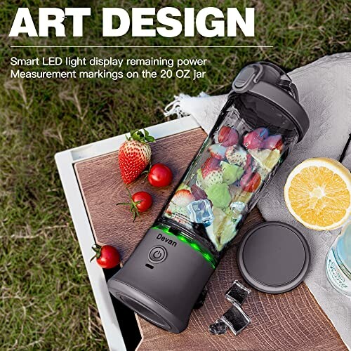 Portable blender with fruits and ice on a table outdoors.