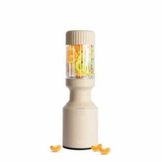 Portable blender with fruits inside and orange slices around.