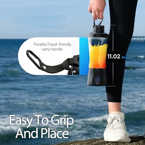 Person holding a portable bottle with drink by the ocean.